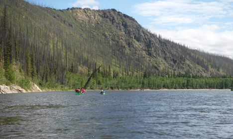 canoeists paddle down river with mountainous northern drop